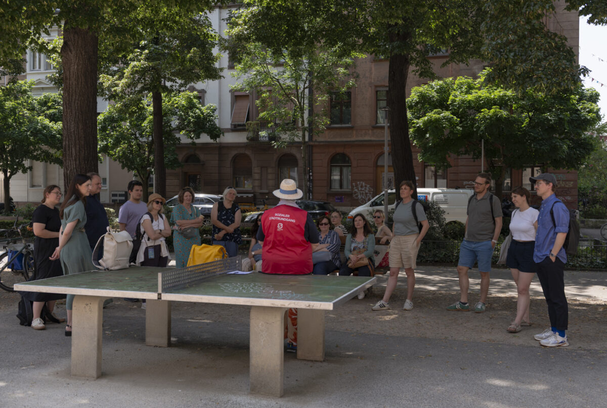 Eine Gruppe von Menschen steht um einen Tischtennistisch in einem Park.