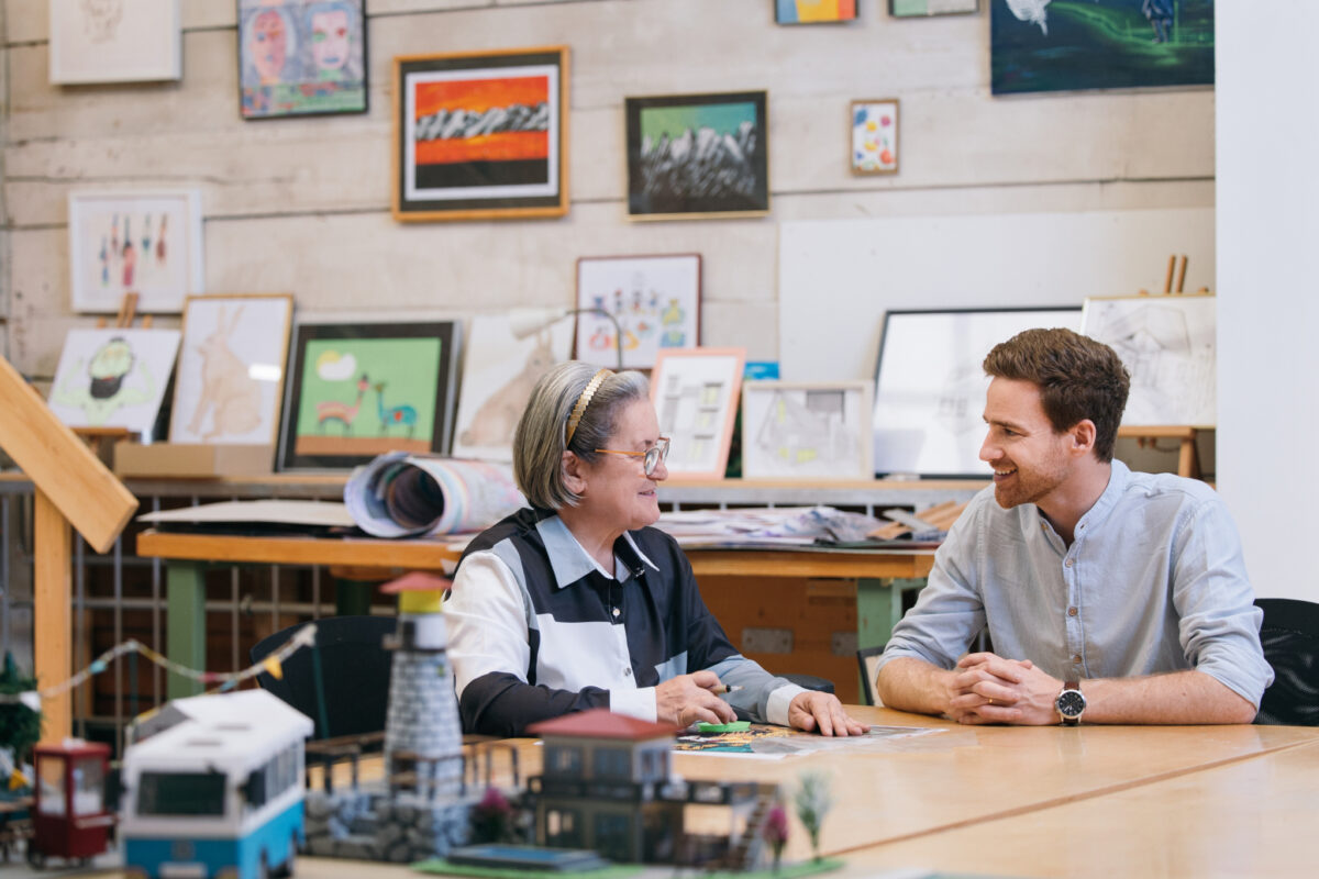 Zwei Personen unterhalten sich in einem Raum voller Kunstwerke.
