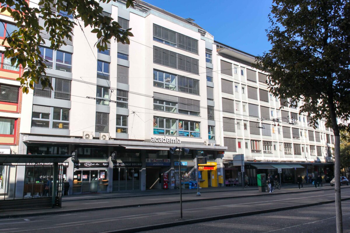 Ein mehrstöckiges Gebäude mit Geschäften und Restaurants im Erdgeschoss.