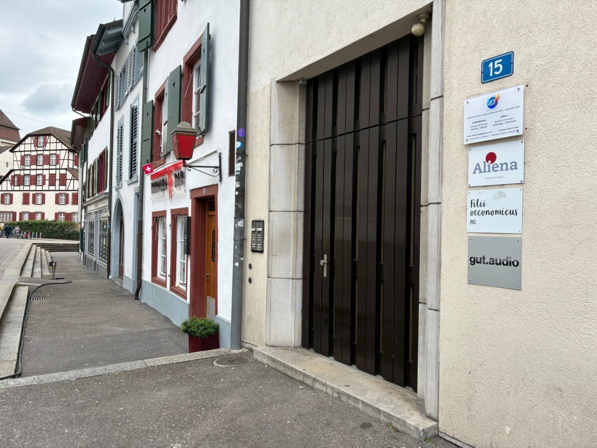 Ein Gebäude mit mehreren Schildern und einer schwarzen Tür in einer europäischen Stadt.