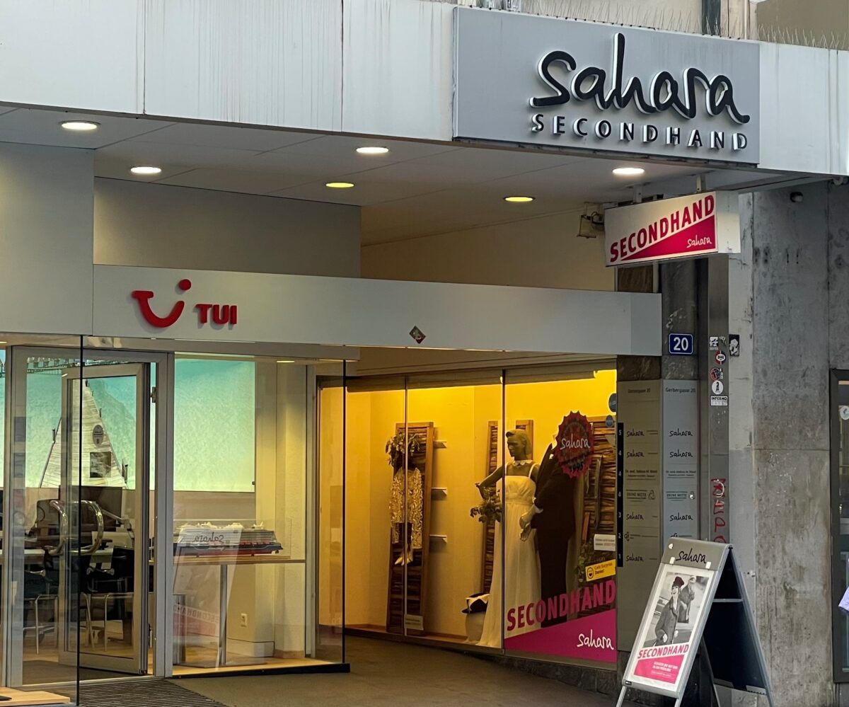 Ladenfront von "Sahara Secondhand" mit Schaufensterpuppen und Kleidung.