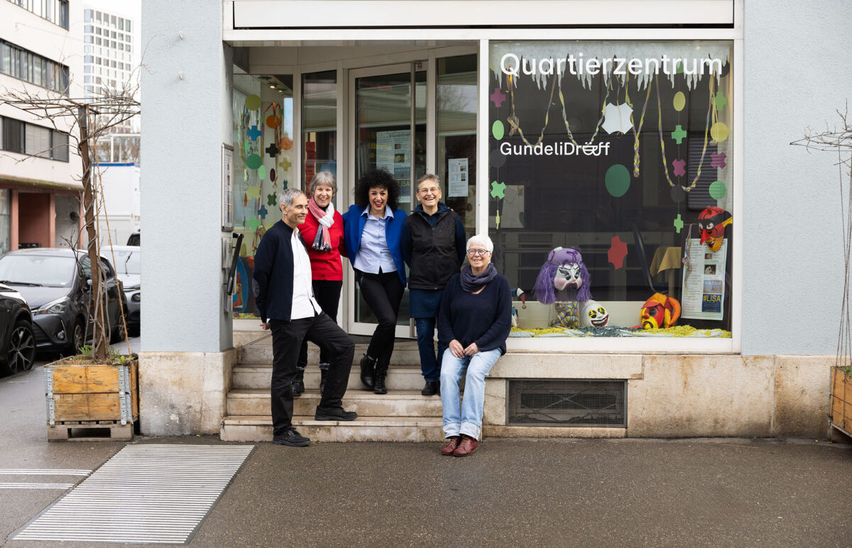 Fünf Personen stehen vor einem bunt dekorierten Quartierzentrum.
