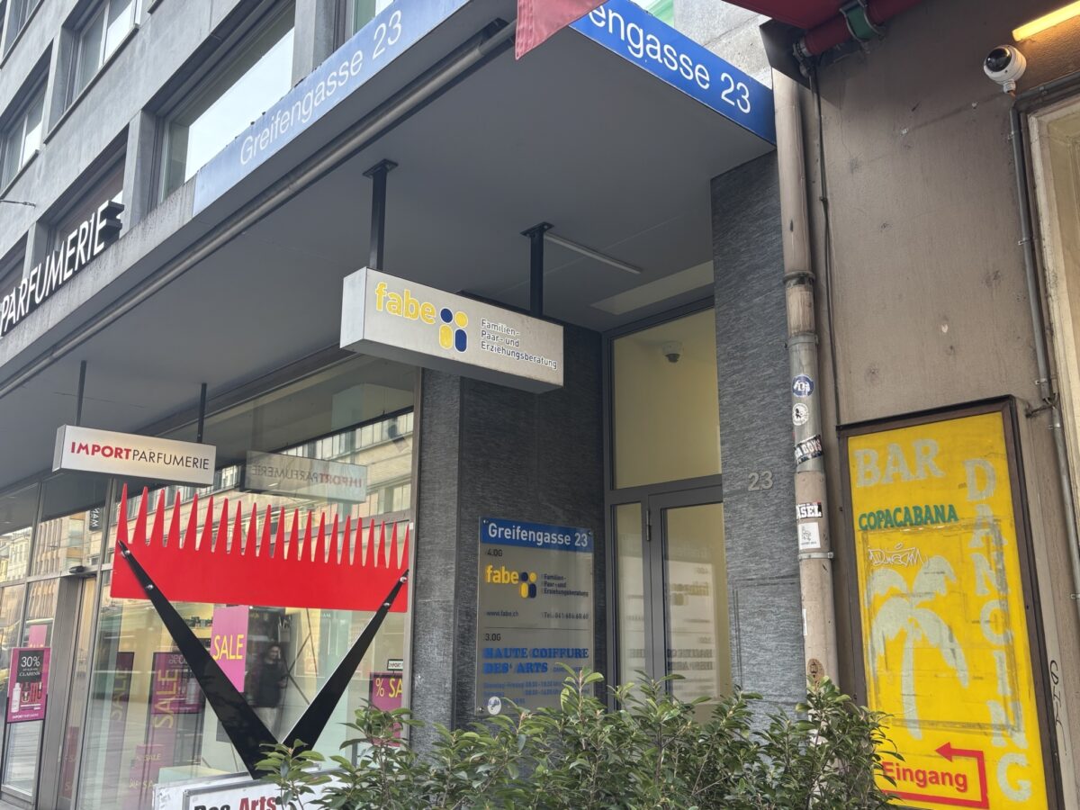 Ein Geschäft in der Greifengasse 23 mit verschiedenen Schildern und Werbetafeln.