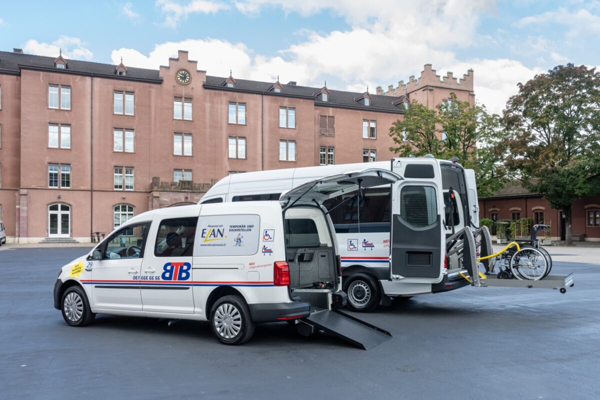 Ein barrierefreier Kleinbus mit Rampe und Fahrradhalterung vor einem Gebäude.
