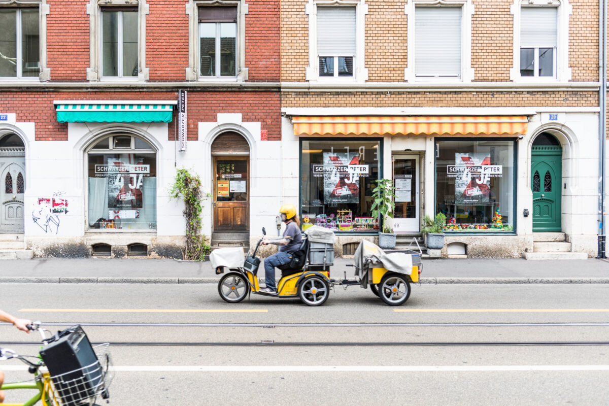 Ein Lieferfahrer auf einem Dreirad fährt an einem Geschäft vorbei.