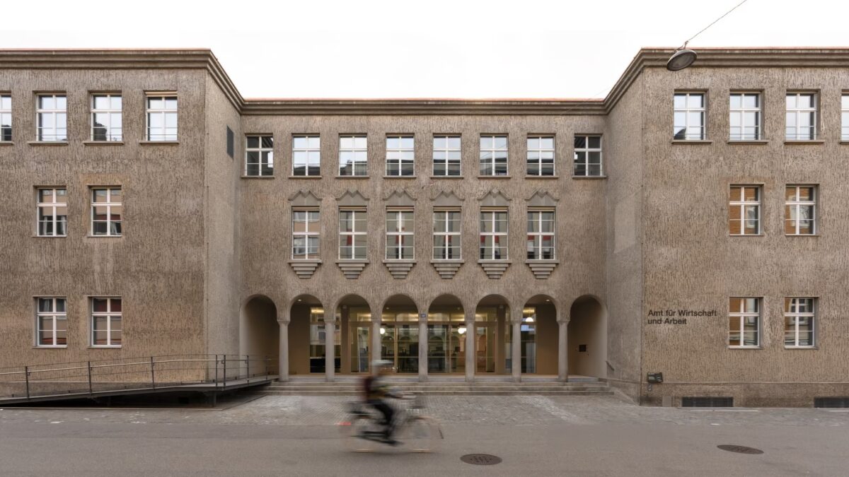 Ein Gebäude mit Arkaden und einem Radfahrer im Vordergrund.