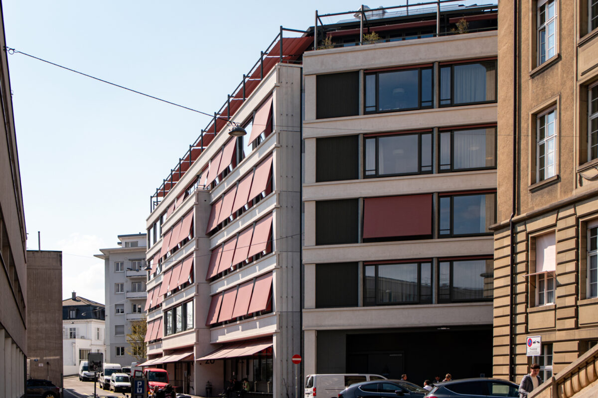 Moderne Gebäude mit großen Fenstern und parkenden Autos davor.