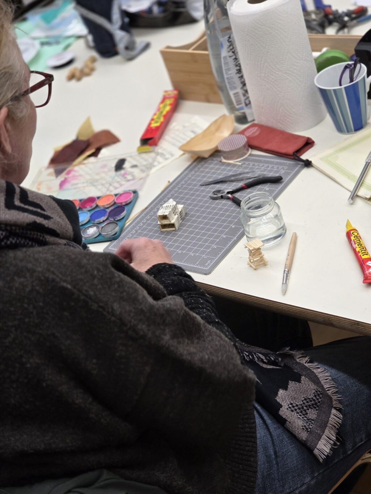 Eine Person arbeitet konzentriert an einem Modell auf einem Arbeitstisch.