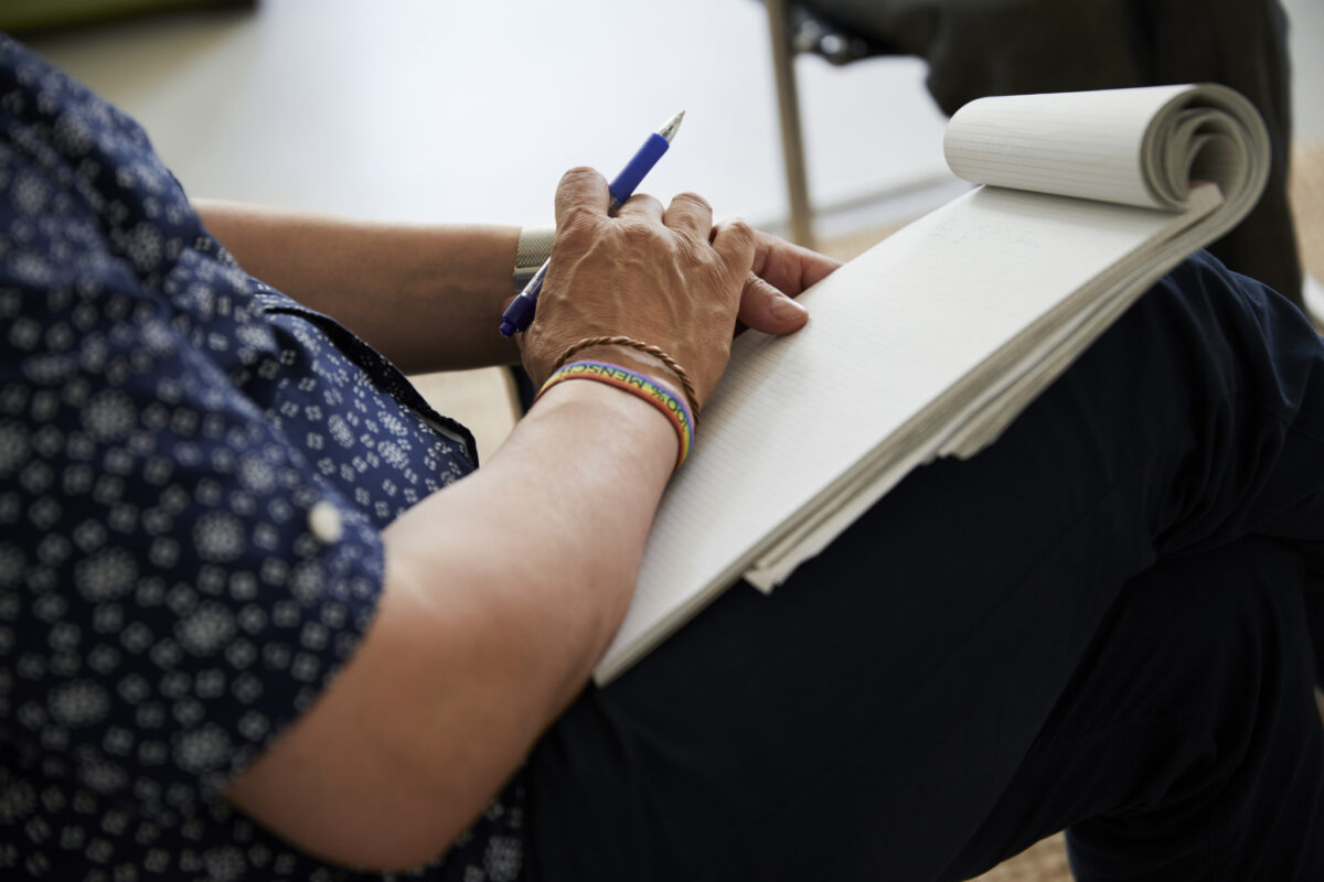 Eine Person schreibt mit einem Stift in ein Notizbuch.