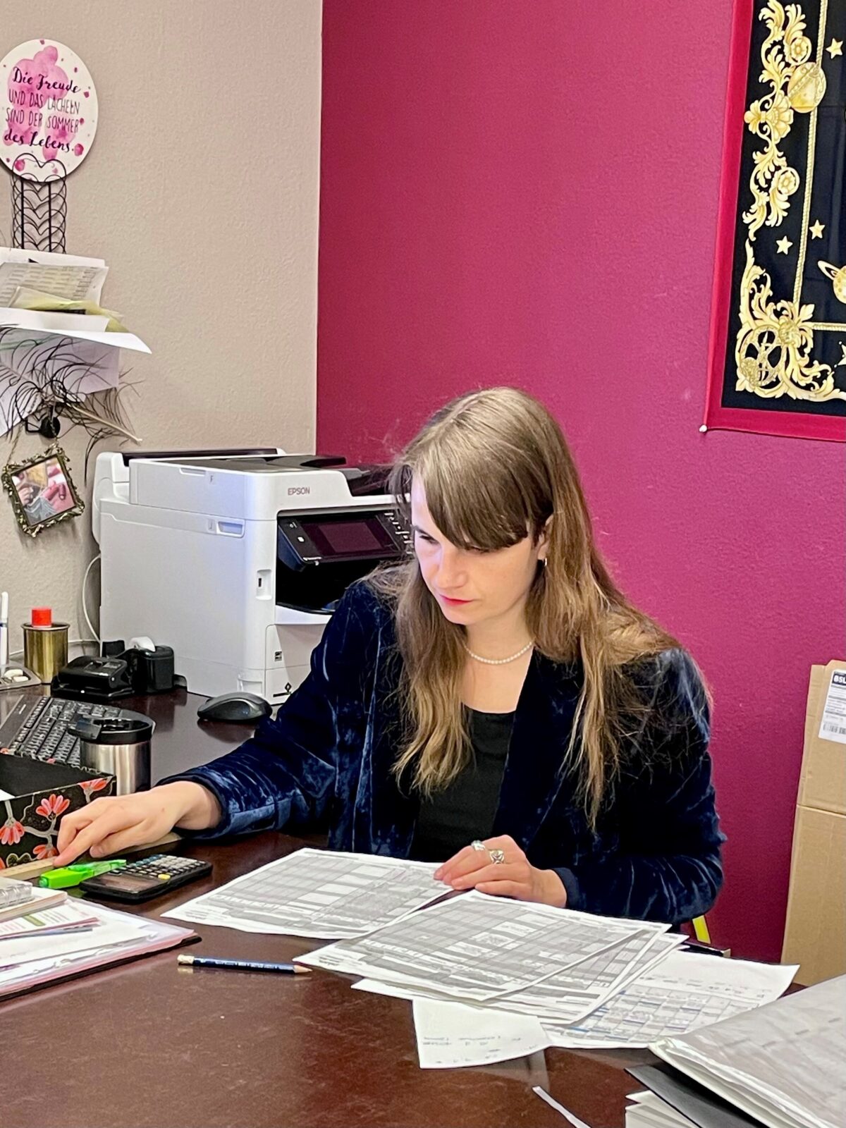 Eine Frau arbeitet konzentriert an einem Schreibtisch mit Dokumenten und einem Drucker.