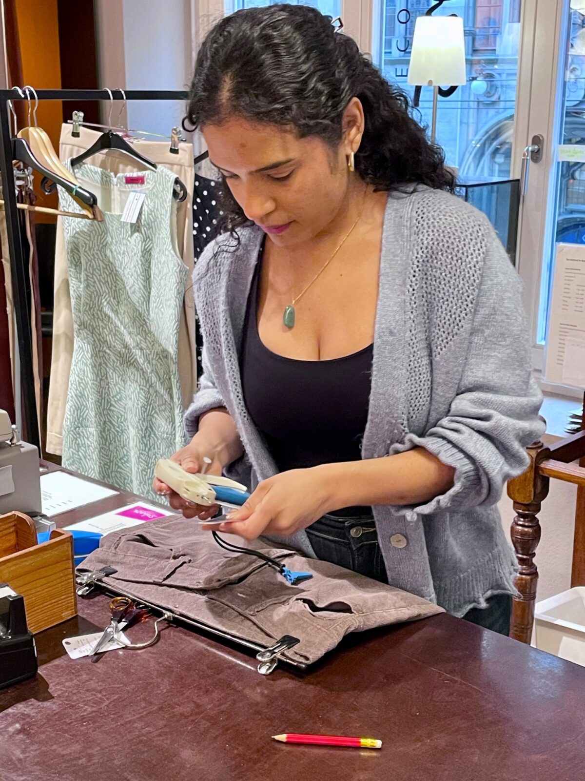 Eine Person näht konzentriert an einem Stoffstück auf einem Tisch.