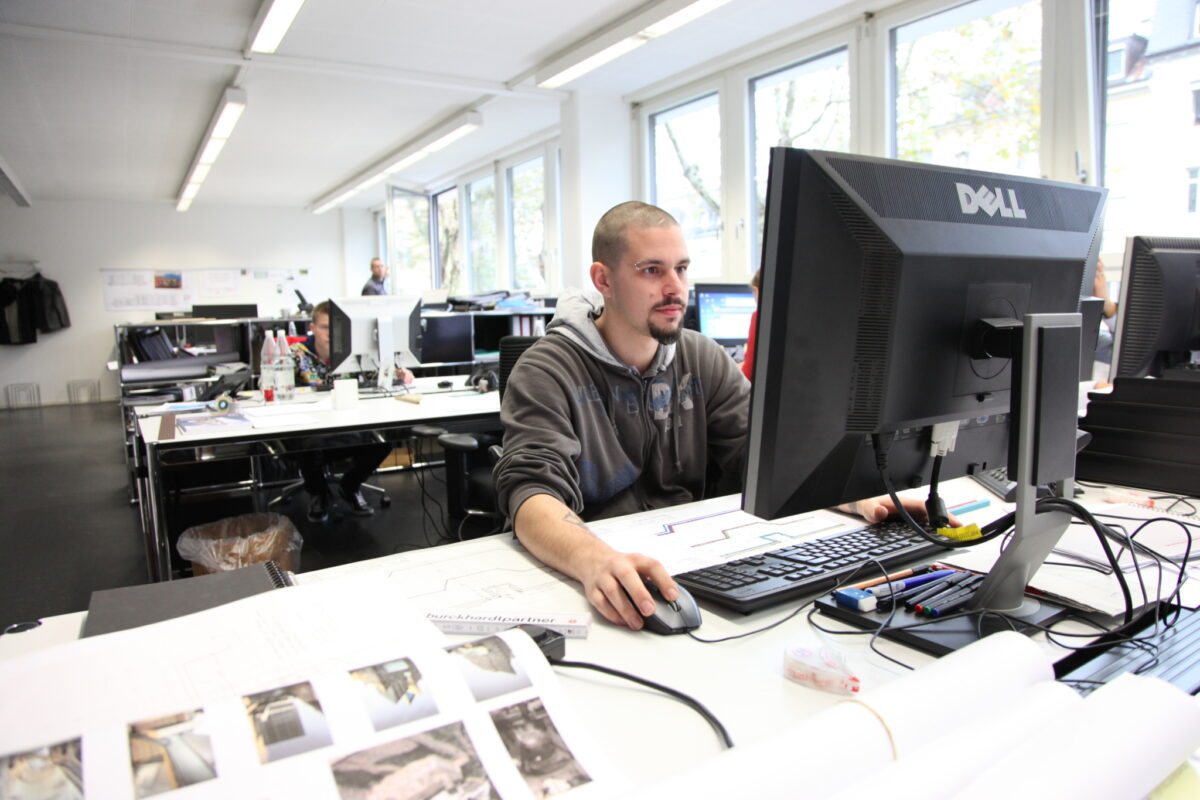 Ein Mann arbeitet konzentriert an einem Computer in einem Büro.