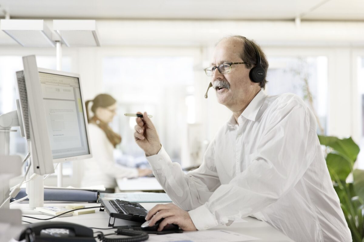 Ein Mann mit Kopfhörern arbeitet konzentriert an einem Computer.