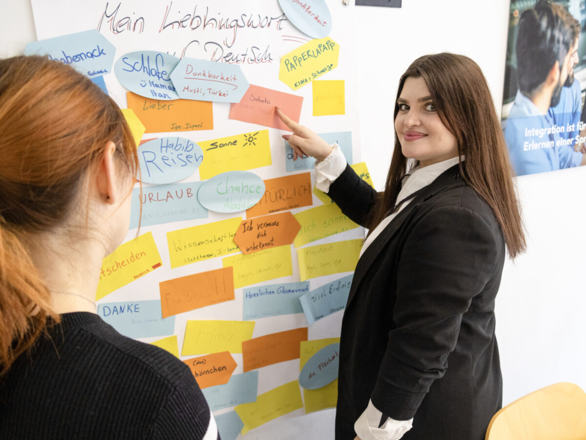 Zwei Frauen betrachten ein Poster mit deutschen Lieblingswörtern.