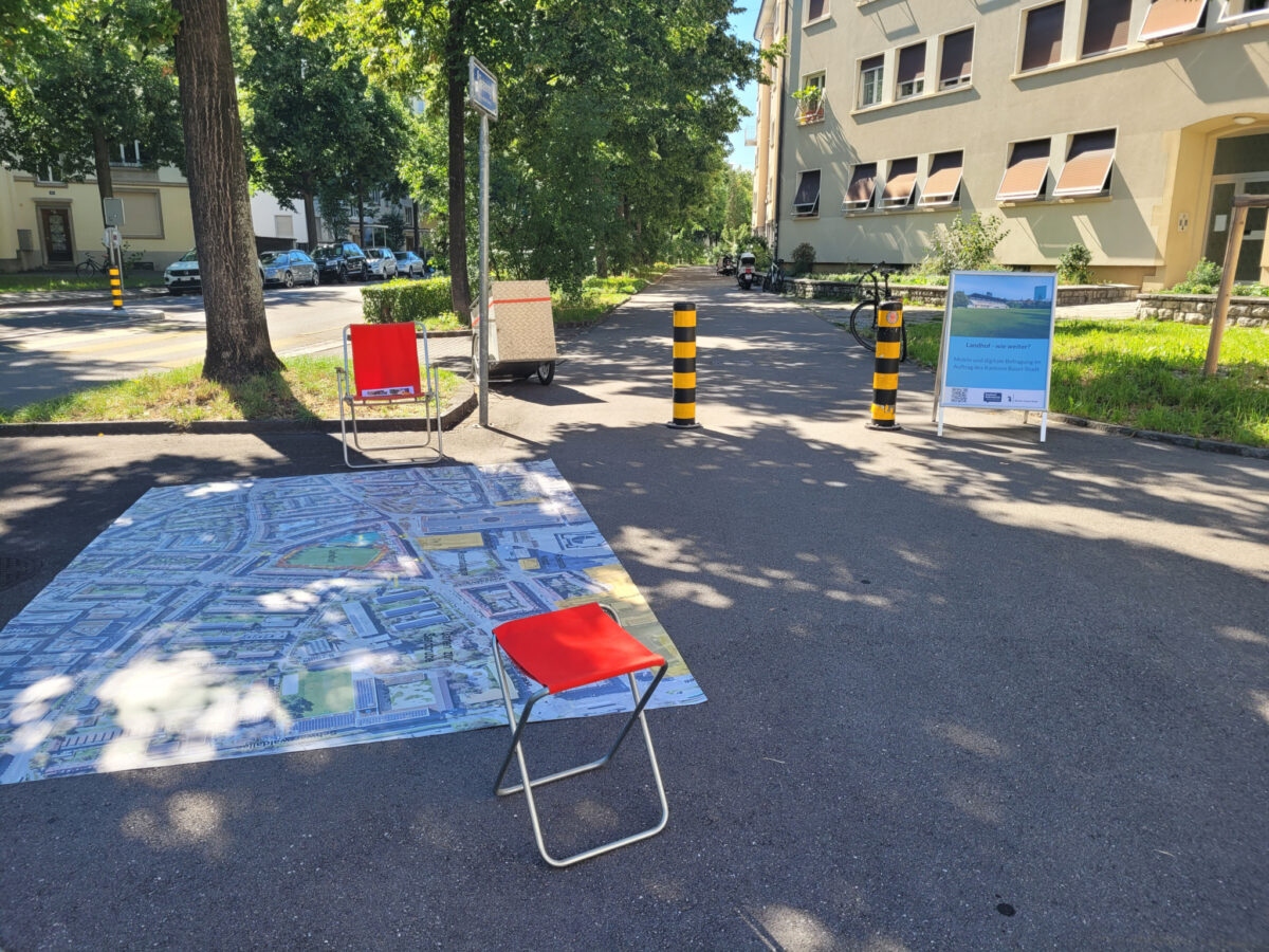 Zwei rote Klappstühle und eine große Straßenkarte auf einer Straße mit Gebäuden im Hintergrund.