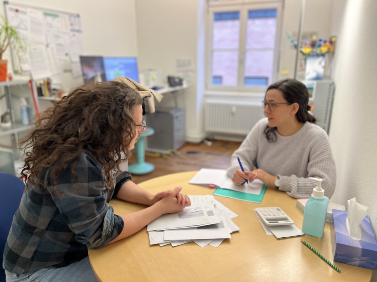 Zwei Personen besprechen Dokumente an einem Tisch.