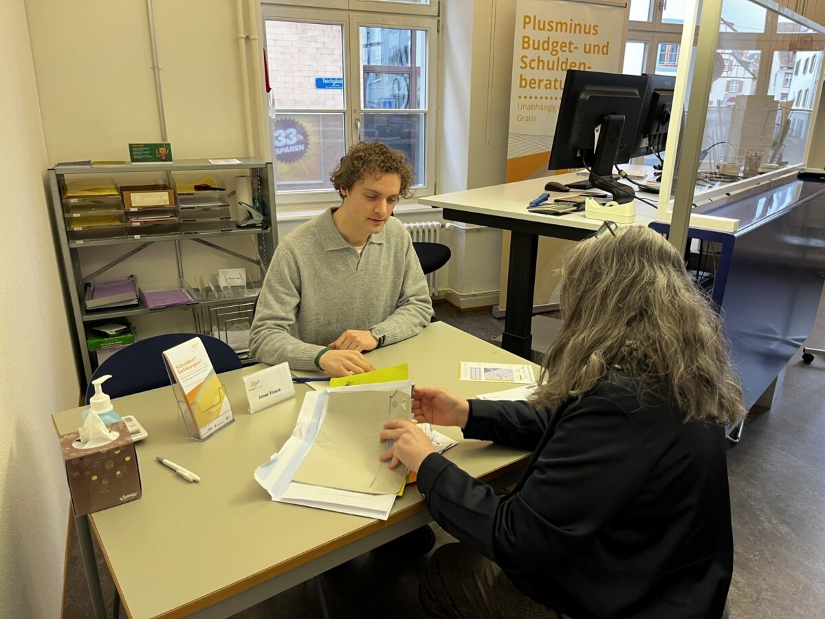 Zwei Personen besprechen Dokumente an einem Beratungstisch.