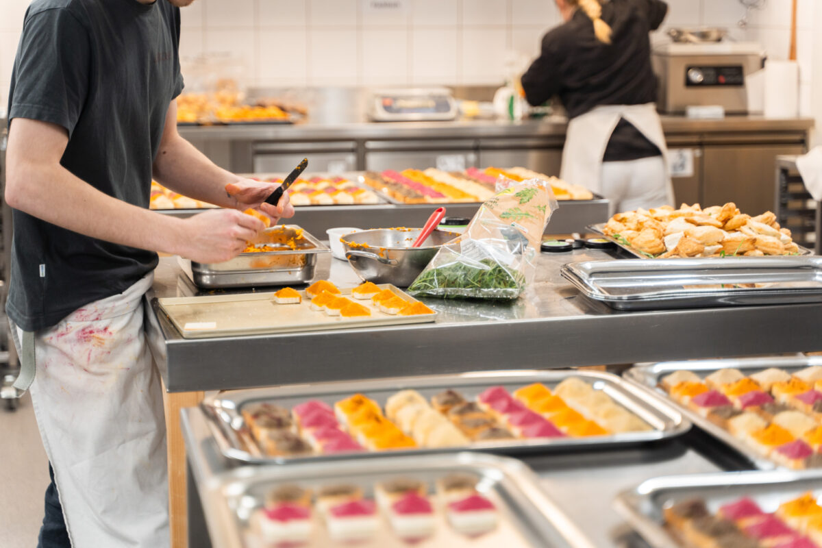 Eine Person bereitet in einer Küche ein Buffet mit verschiedenen Speisen vor.