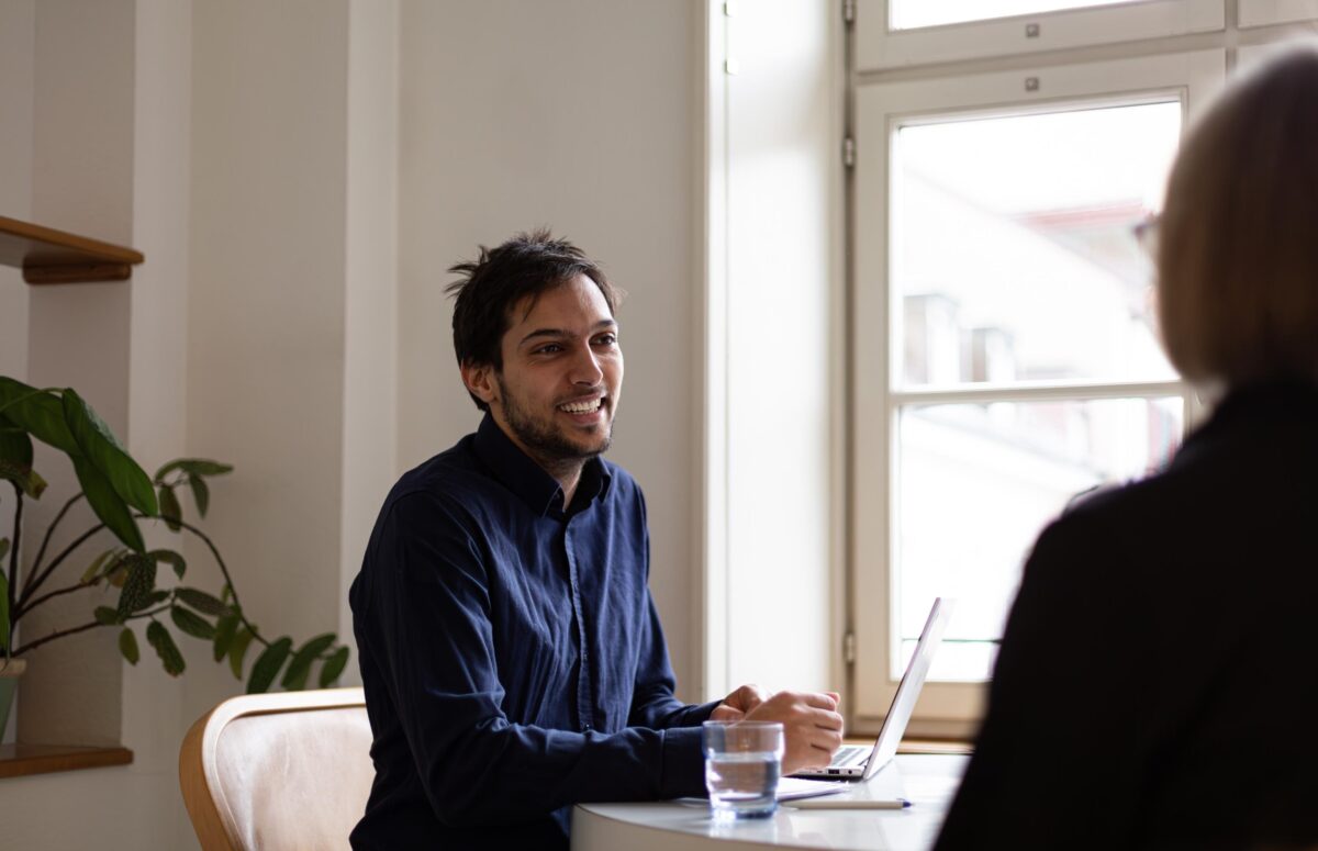 Zwei Personen sitzen an einem Tisch und unterhalten sich freundlich.