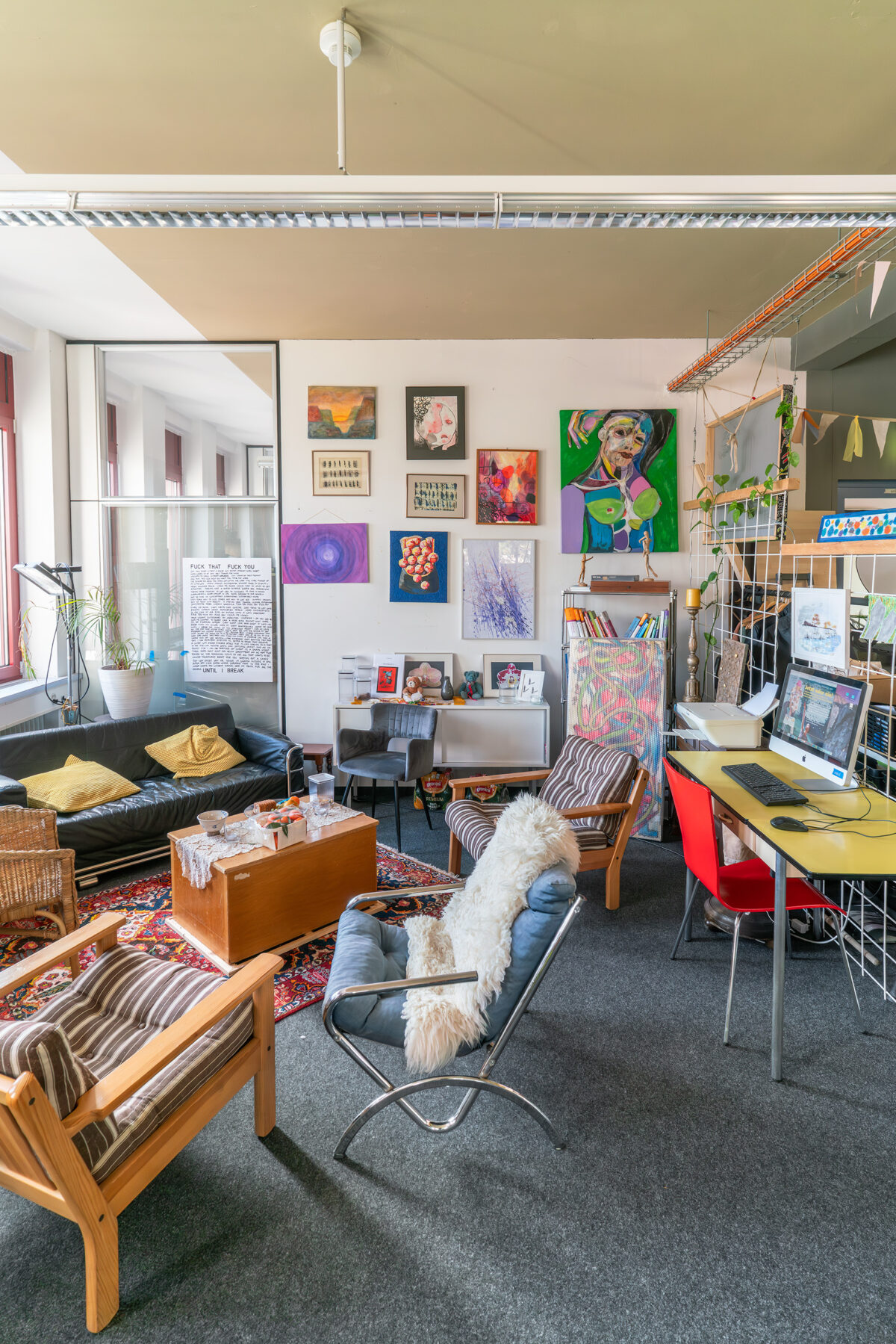 Ein gemütliches Wohnzimmer mit Sofa, Sessel, Kunstwerken und Arbeitsplatz.