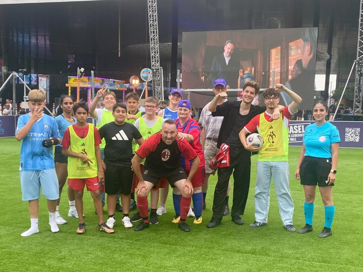 Eine Gruppe von Menschen steht auf einem Fußballfeld und posiert für ein Gruppenfoto.