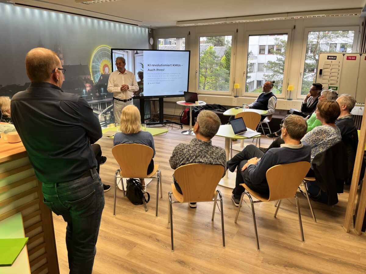 Eine Gruppe von Menschen hört einem Vortragenden in einem Seminarraum zu.