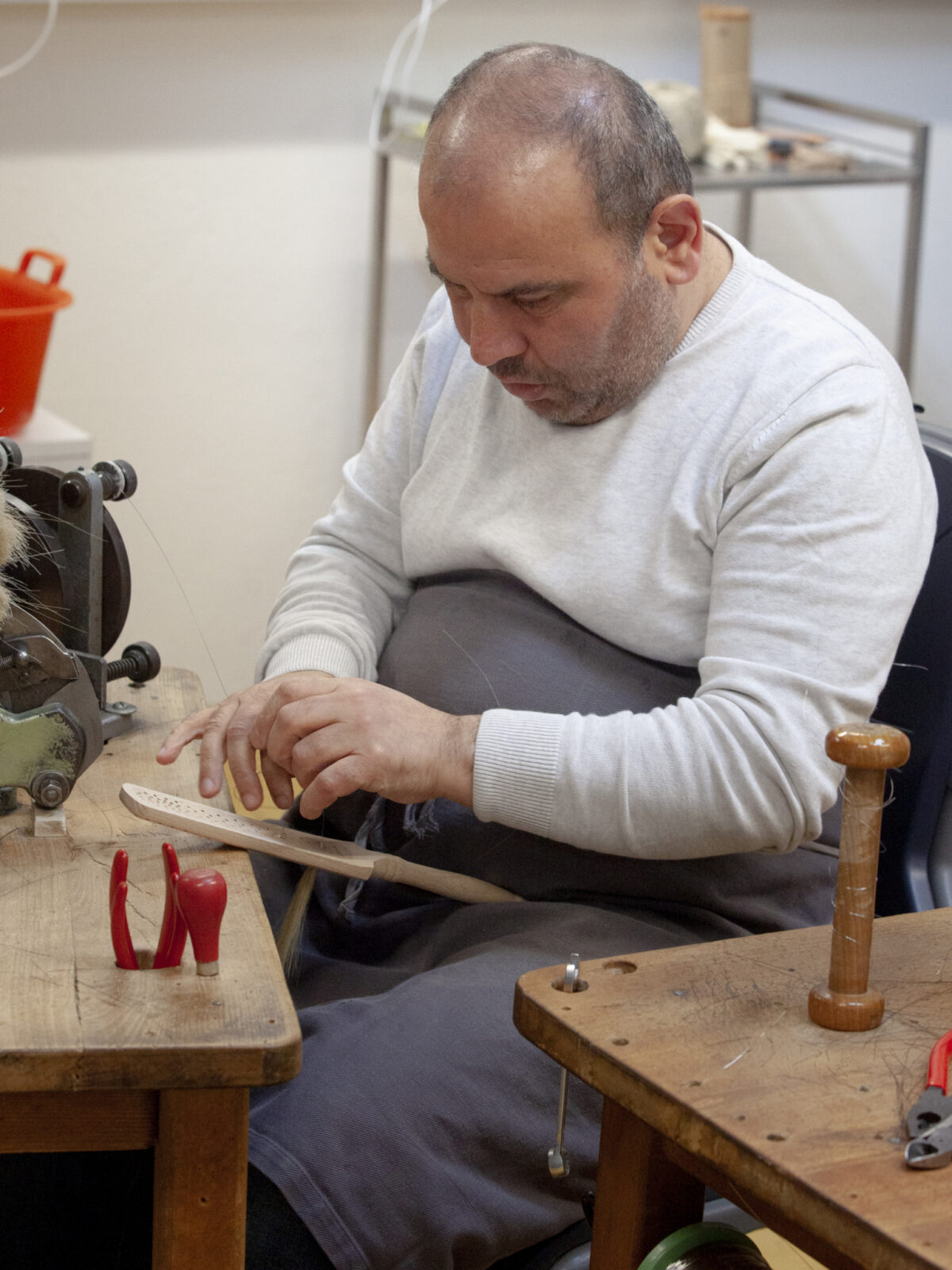 Ein Mann arbeitet konzentriert an einer Werkbank mit verschiedenen Werkzeugen.