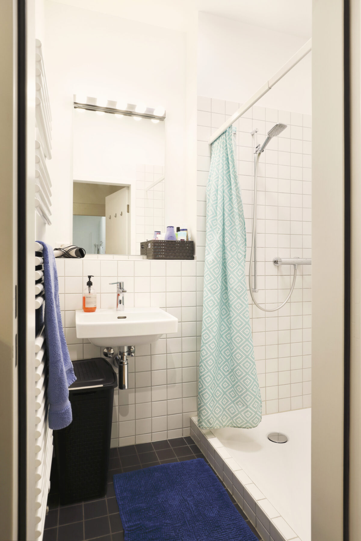 Ein modernes Badezimmer mit Waschbecken, Dusche und blauem Badezimmerteppich.