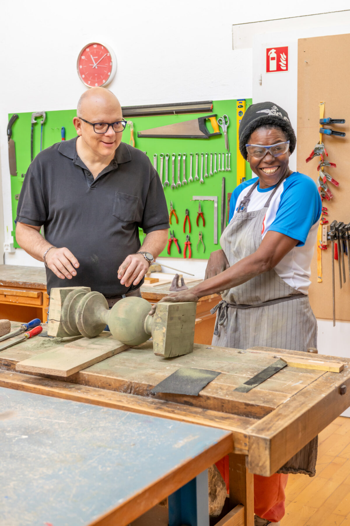 Zwei Personen arbeiten gemeinsam in einer Werkstatt an einem Werkstück.