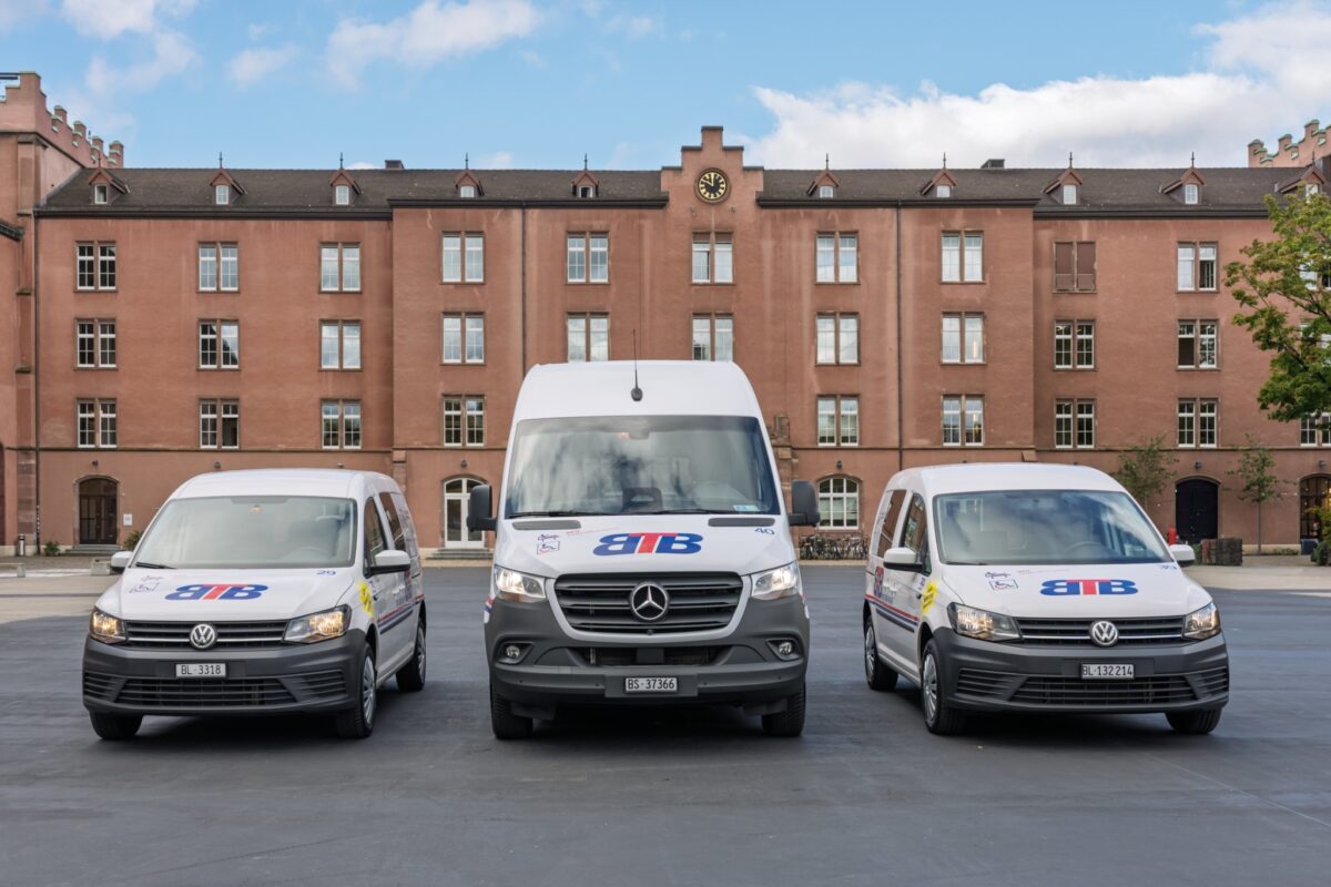 Drei weiße Lieferwagen mit BTB-Logo vor einem roten Gebäude.