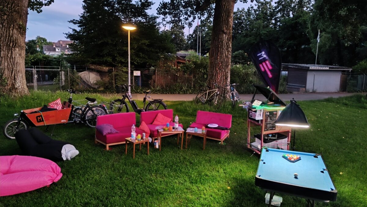 Ein gemütlicher Outdoor-Sitzbereich mit Sofas, Tischen und einem Billardtisch auf einer Wiese.