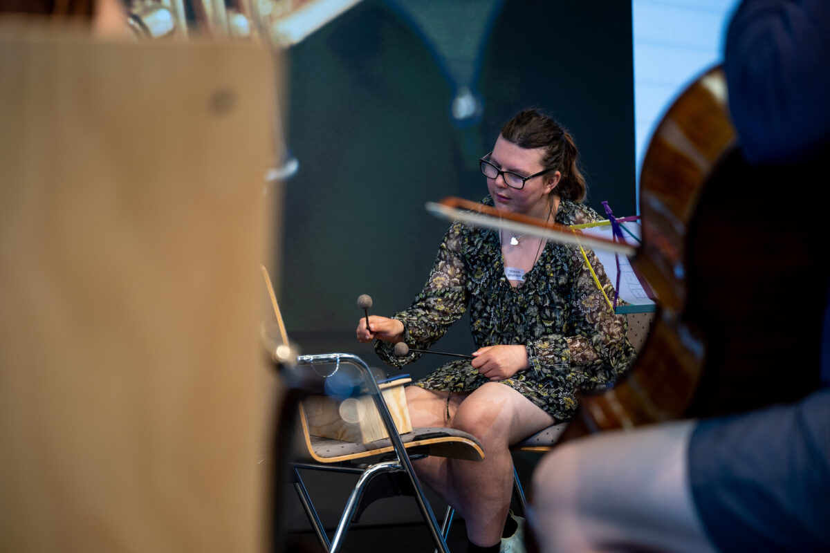 Eine Person spielt konzentriert Percussion-Instrumente auf der Bühne.