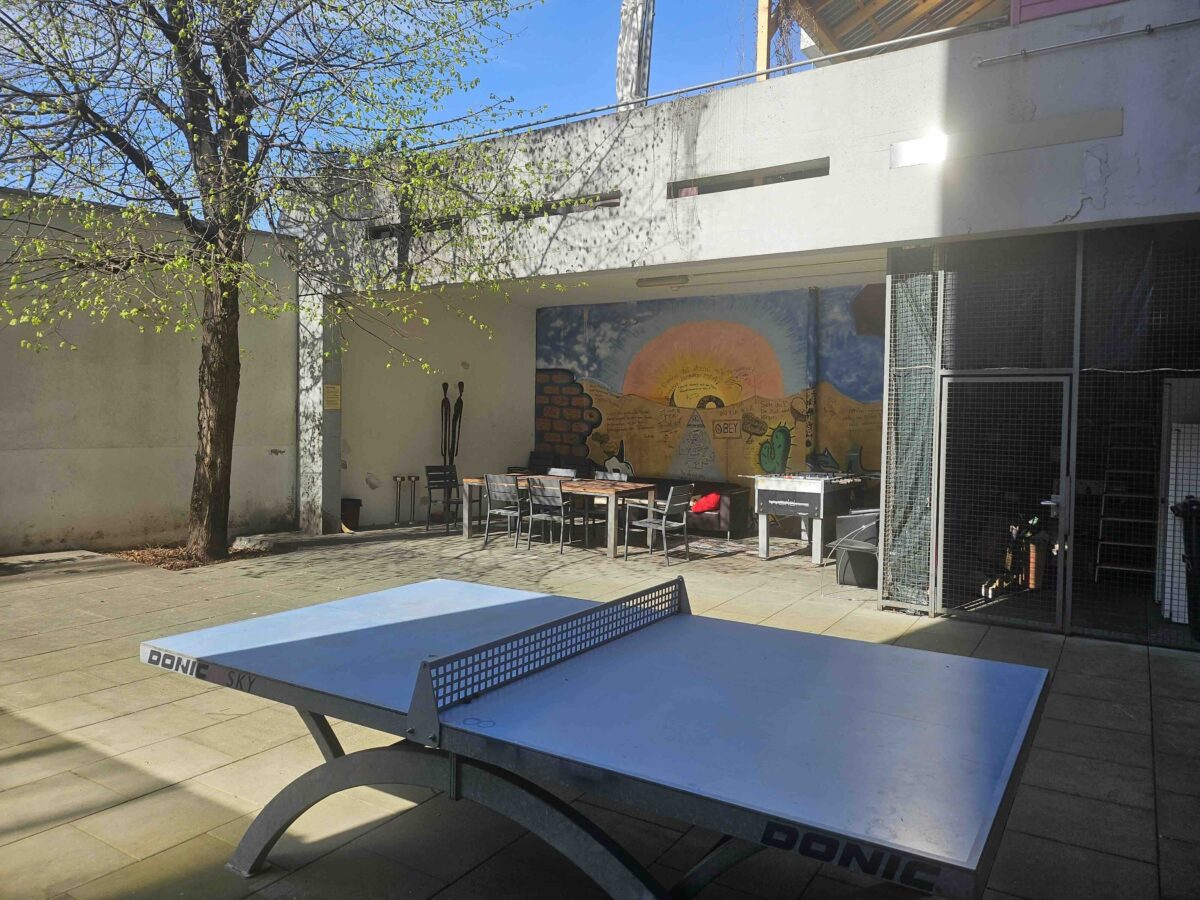 Ein Tischtennis-Tisch steht im Freien vor einem Gebäude mit Wandgemälde.