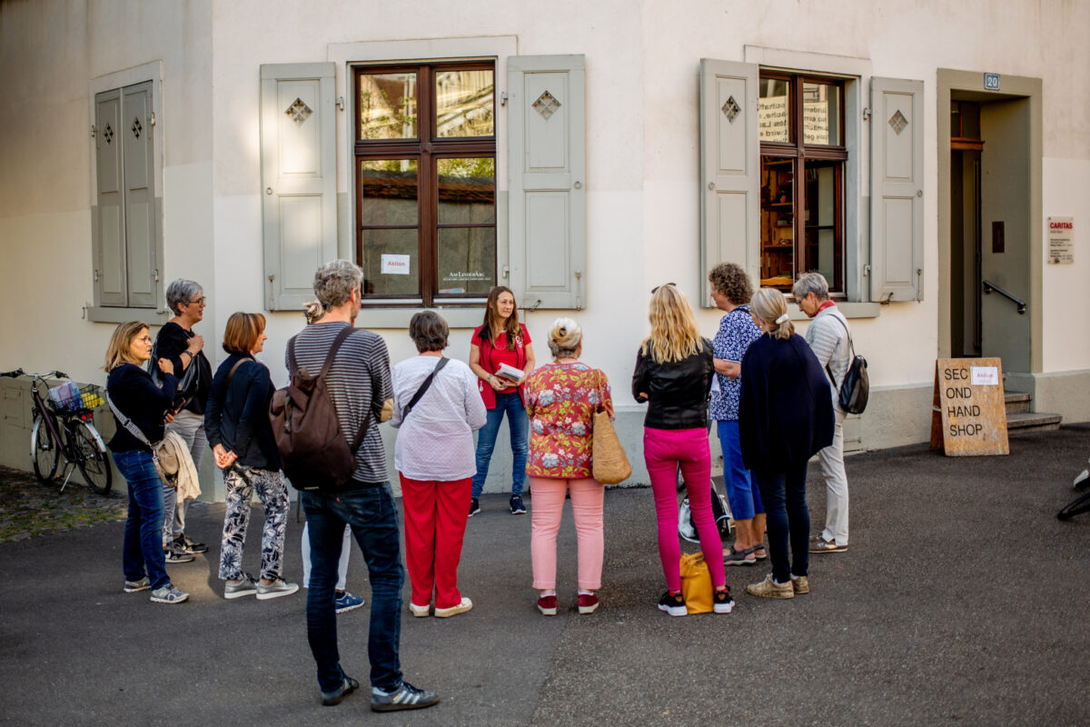Eine Gruppe von Menschen steht vor einem Gebäude und unterhält sich.