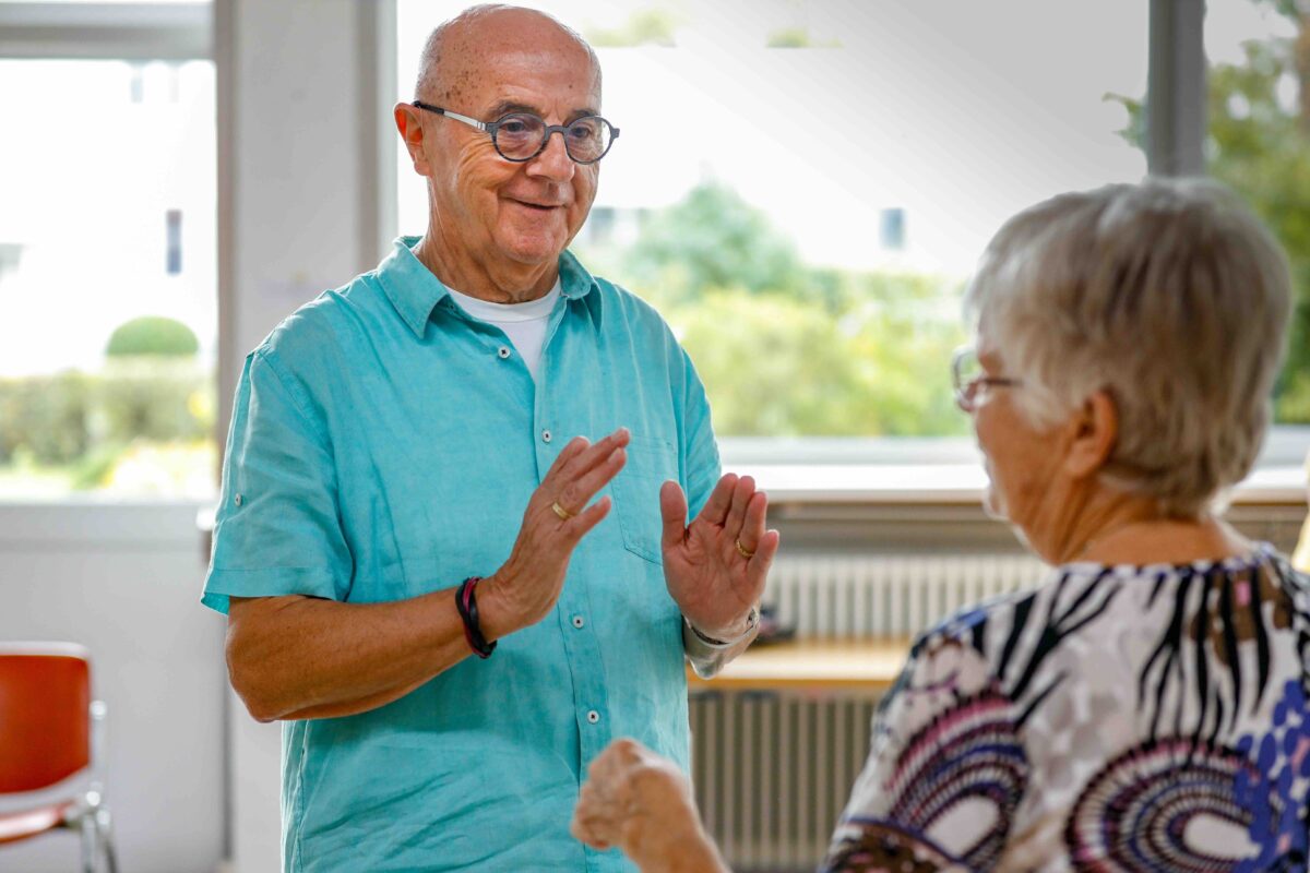 Zwei ältere Menschen unterhalten sich freundlich in einem hellen Raum.