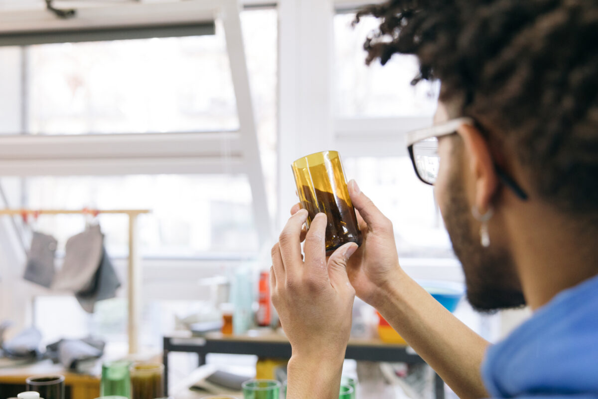 Eine Person hält ein Glas mit Flüssigkeit gegen das Licht.