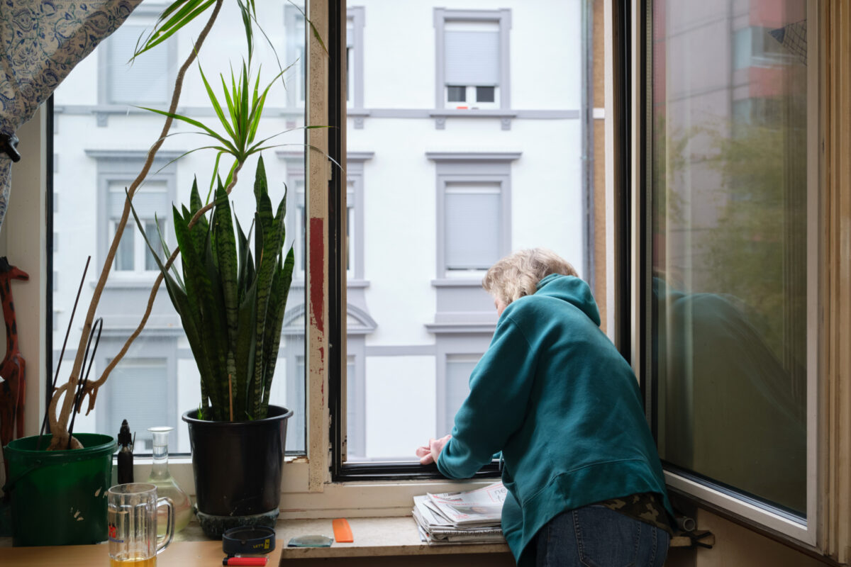 Eine Person sitzt am Fenster und liest eine Zeitung.