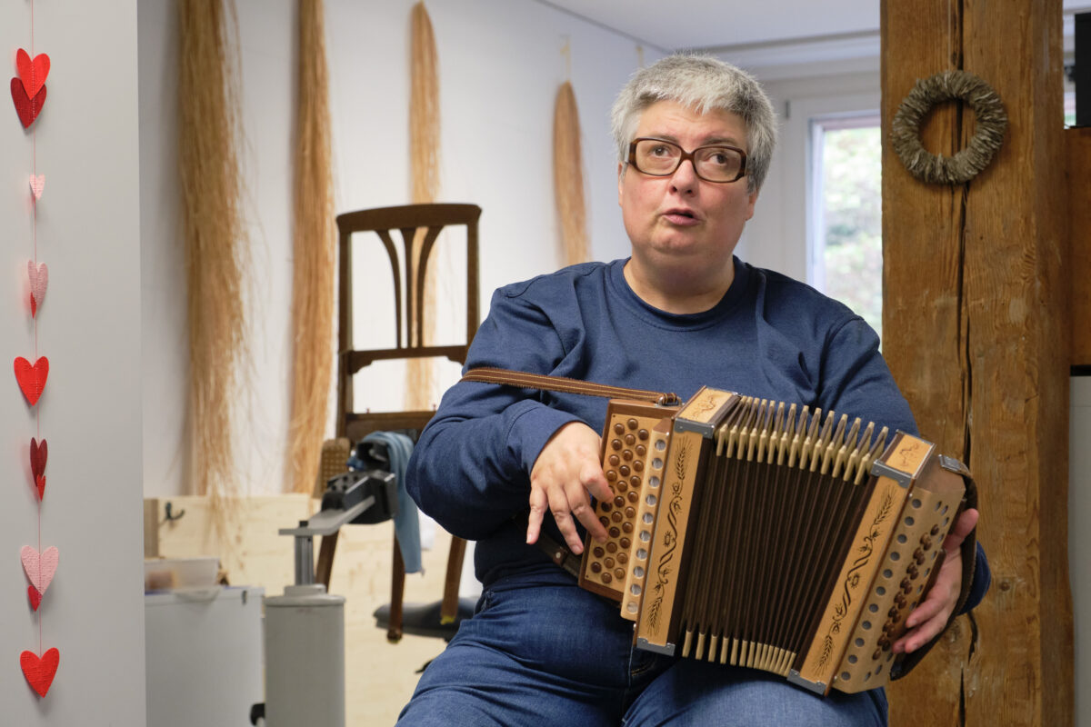 Eine Person spielt eine mit Ornamenten verzierte Akkordeon in einem Raum mit Holzdekor.