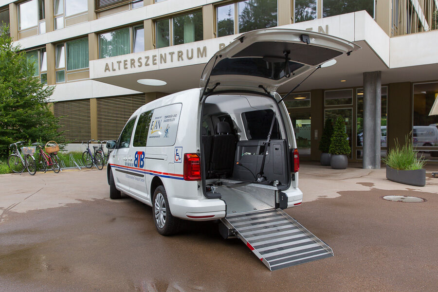 Ein weißer Krankenwagen mit Rampe vor einem Altenzentrum.