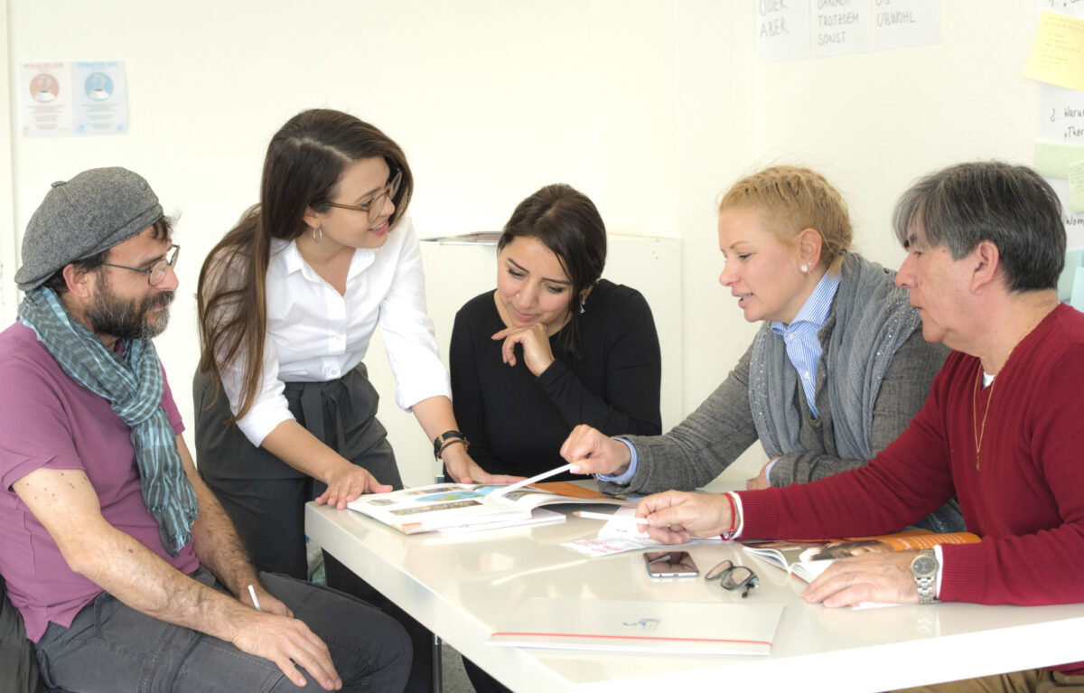 Eine Gruppe von Menschen bespricht etwas an einem Tisch.