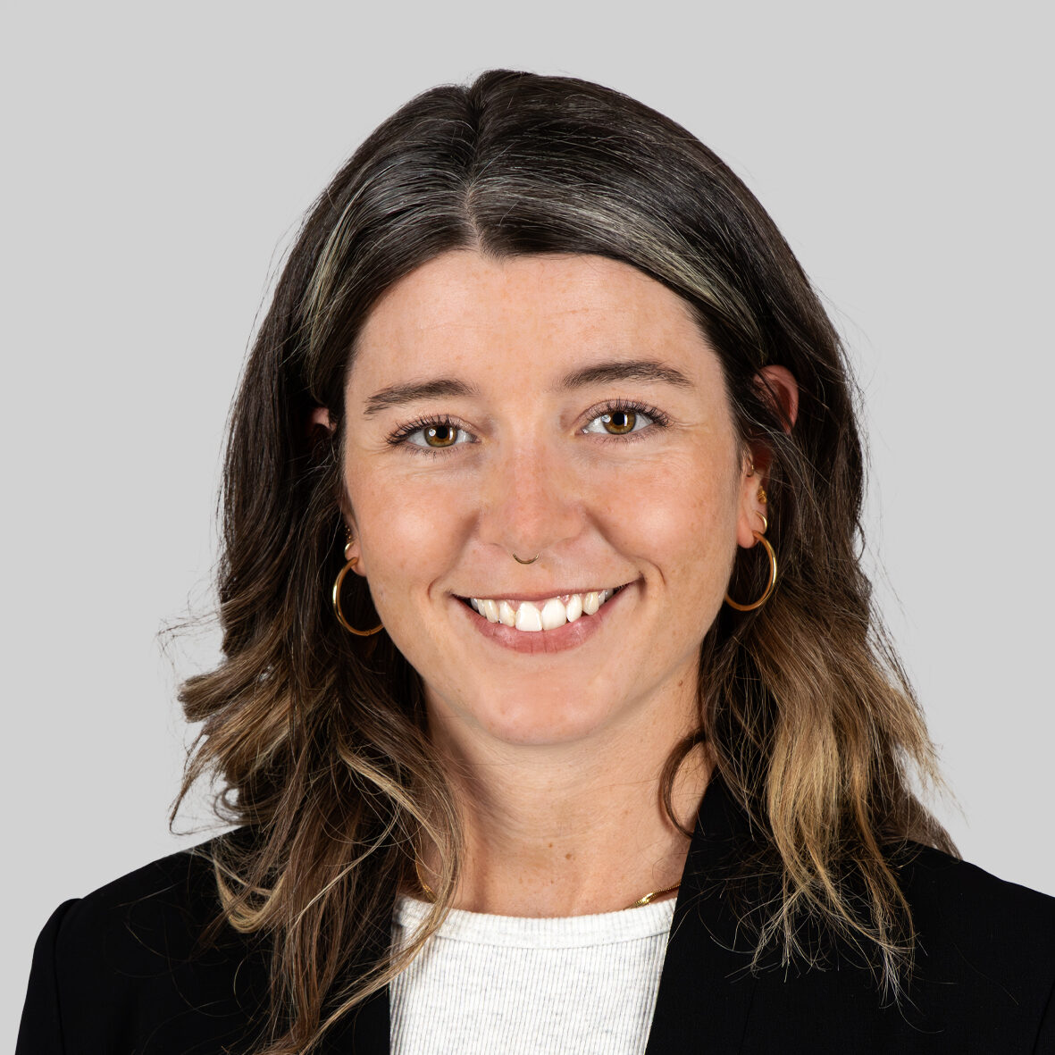 Eine lächelnde Frau mit langen Haaren und goldenen Ohrringen.