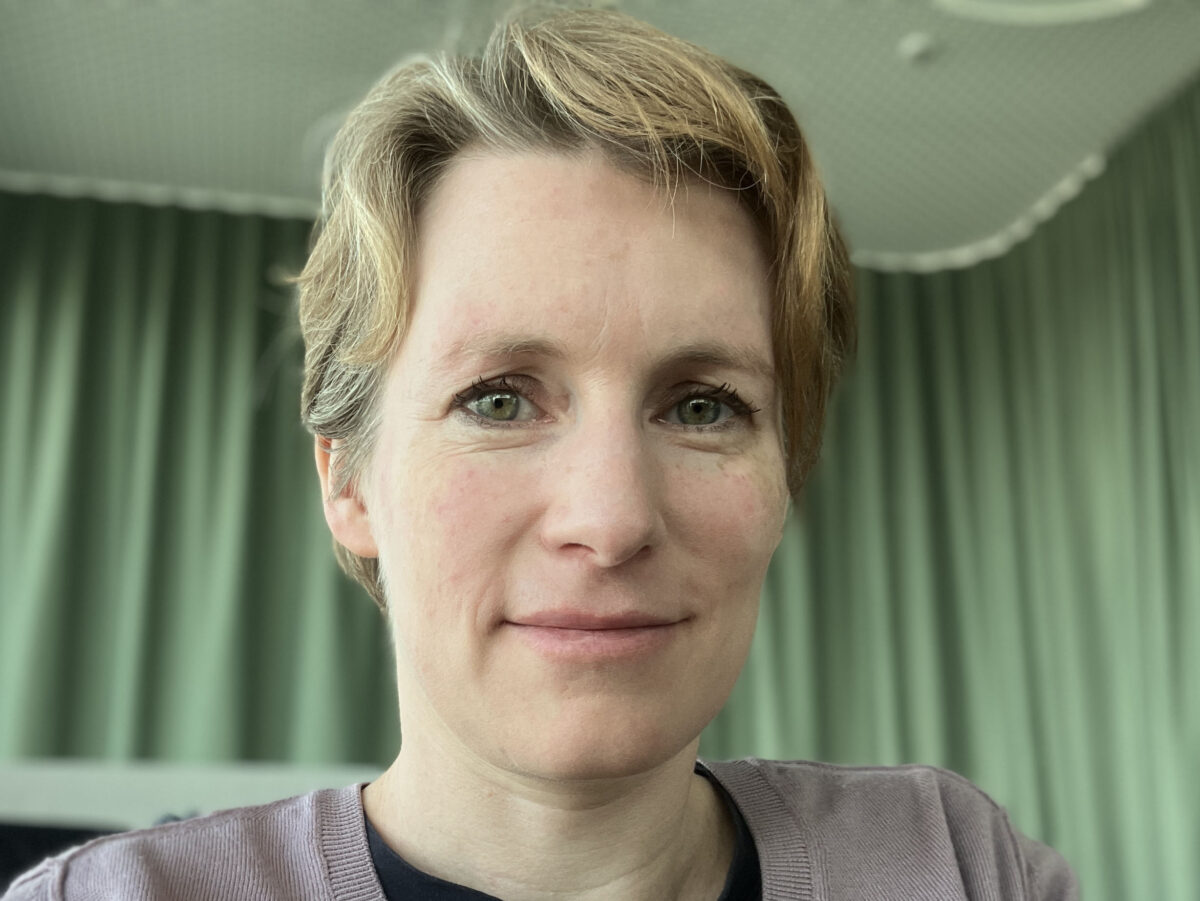 Eine Frau mit kurzen blonden Haaren lächelt in die Kamera.